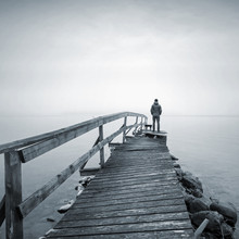 Man On The Old Broken Wooden Pier Starring At The Foggy Sea