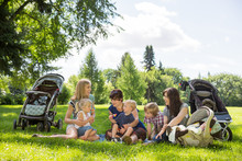 Mothers And Children Enjoying Picnic In Park
