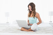 © lightwavemedia - Relaxed woman using laptop in bed