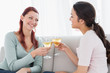 © lightwavemedia - Happy young female friends toasting wine glasses at home