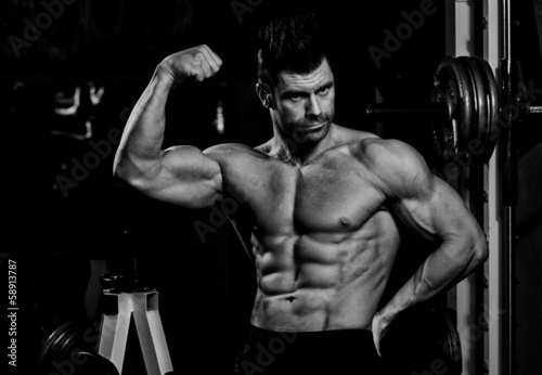 Board z aluminiowym obramowaniem Czarno-białe zdjęcie mężczyzn pokazano jego biceps w sali gimnastycznej