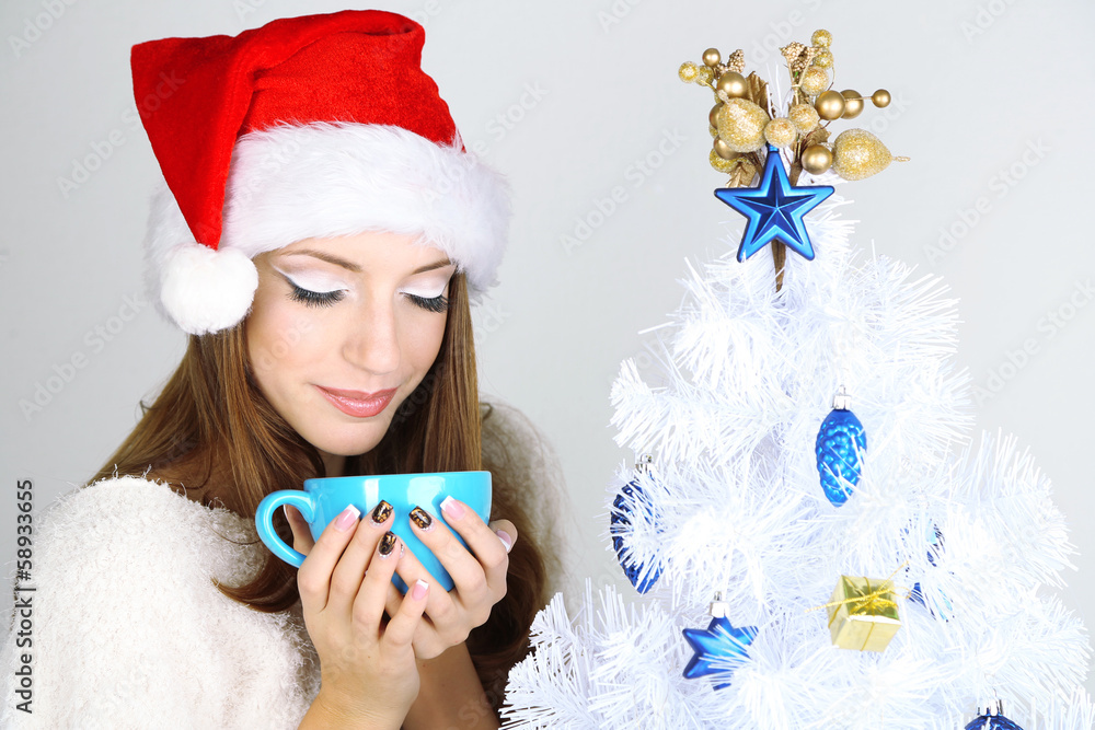 Beautiful smiling girl near Christmas tree with cup
