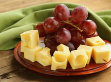 Wooden Plate With Cheese (Maasdam) And Red Grapes
