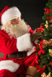 © Milles Studio - Santa Claus decorating Christmas tree in dark room