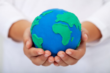 our home - child holding earth made of clay