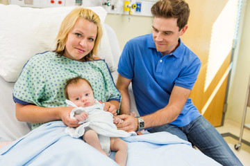 Fototapete - Woman With Newborn Baby Girl Sitting By Man In Hospital