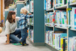 © Tyler Olson - Teacher Assisting Boy In Selecting Book From Bookshelf