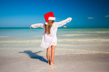 Wall Mural - Back view of Little cute girl in red hat santa claus on the