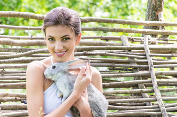 Wall Mural - Young happy woman embracing little rabbit outdoors