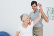 © lightwavemedia - Physiotherapist stretching a smiling senior woman's arm