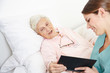 Geriatric nurse reading book to senior woman