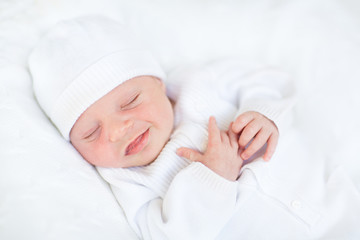 sweet sleeping smiling newborn baby in a white hat