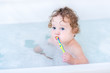 © famveldman - Adorable baby girl with big blue eyes brushing her teeth taking