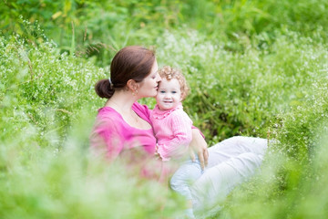 Wall Mural - Pregnant mother and her baby daughter relaxing in the garden