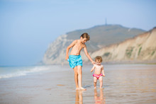Two Kids, Brother And Baby Sister, Running At A Beautiful Beach
