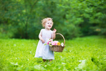 Wall Mural - Beautiful baby girl in a sunny garden with a flower basket