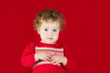 Wall Mural - Beautiful girl in a warm knitted sweater on red background