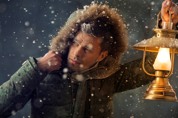 Brutal man walking under snowstorm at night lighting his way wit