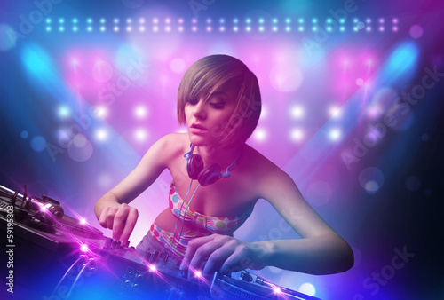 Board z aluminiowym obramowaniem Disc jockey miksująca muzykę na gramofonach na scenie ze światłami i