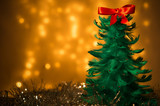Dekoracja świąteczna - zielona choinka z piórek na tle lampek