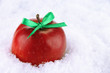 Red apple with bow in snow close up