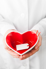 Fototapete - red heart shape with empty label in hands