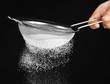 Sieve and powdered sugar on black background