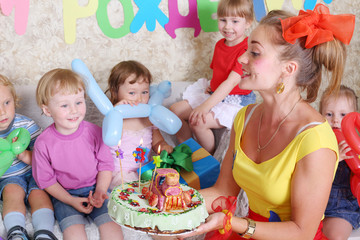 Woman holds birthday cake for little five kids at children party