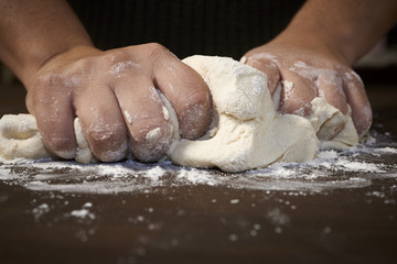 woman's hands kneading dough on wooden table