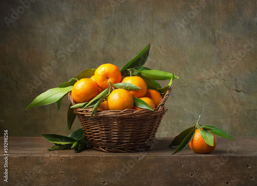 pomaranczowe-mandarynki-w-wiklinowym-koszu-na-stole