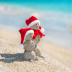 Canvas Print - Snowmans couple at sea beach in christmas hat. New years holiday