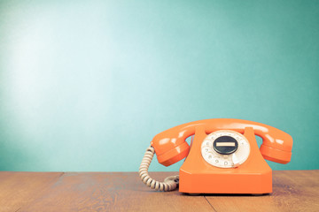 Fototapete - Retro orange telephone on table front mint green wall background