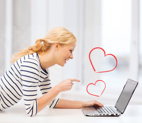 smiling student girl pointing her finger at laptop