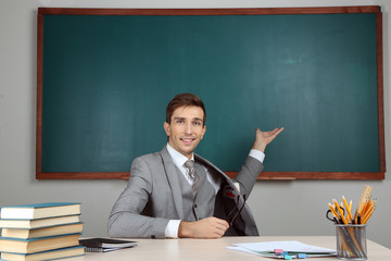 Wall Mural - Young teacher sitting in school classroom