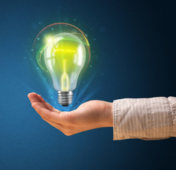 Fototapete - Glowing lightbulb in the hand of a woman