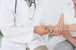 © lightwavemedia - Mid section of a physiotherapist examining a woman's wrist
