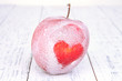 Holiday apple with frosted heart on wooden background