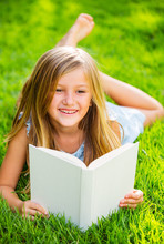 Cute Little Girl Reading Book Outside On Grass