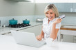 © lightwavemedia - Cheerful woman doing online shopping in the kitchen