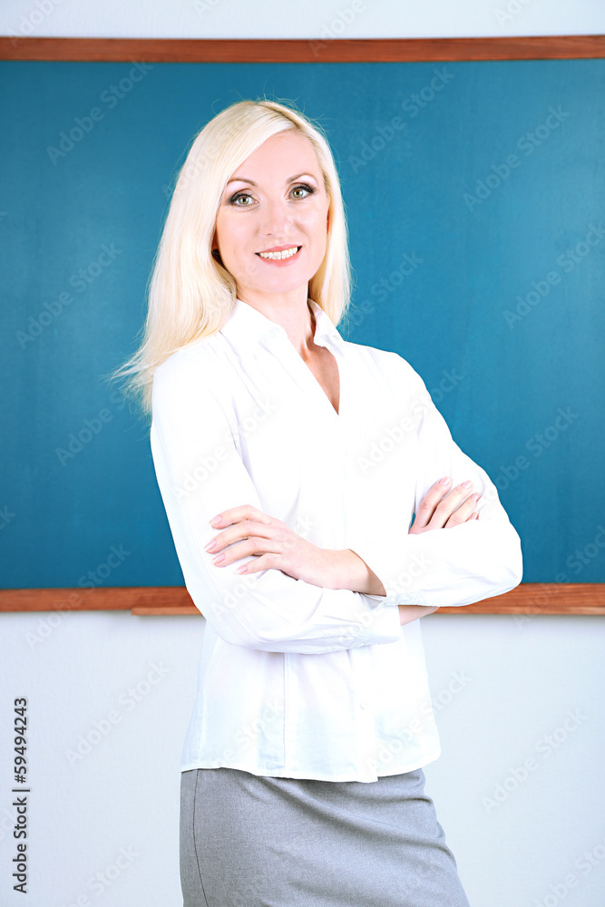 School teacher near blackboard in classroom