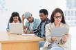 © WavebreakMediaMicro - Concentrated woman using digital tablet with colleagues behind i
