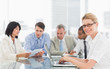 © WavebreakmediaMicro - Businesswoman using her laptop during a meeting looking at camer
