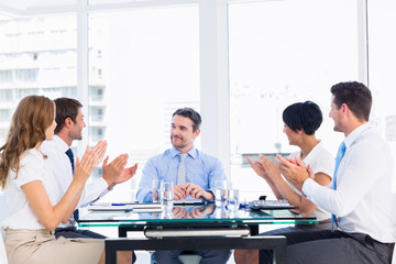 Wall Mural - Executives clapping around conference table