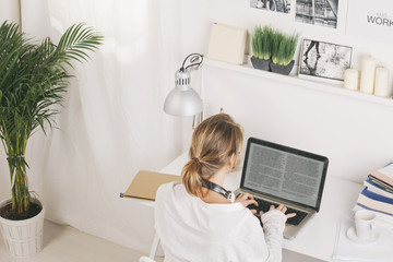 Back view of mature businesswoman working with laptop at home.