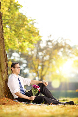 Canvas Print - Handsome guy with flowers sitting on a grass and relaxing