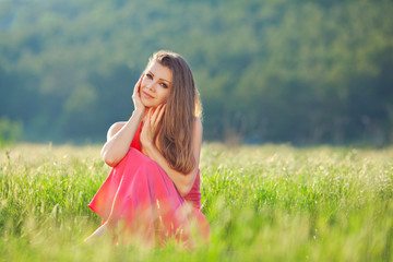 Wall Mural - Portrait of a woman in red on a background of sky and grass