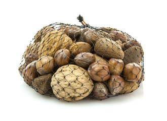 Mix nuts - walnuts, hazelnuts, almonds in a net bag on a white b