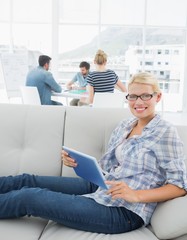 Wall Mural - Woman using digital tablet with colleagues in background at crea