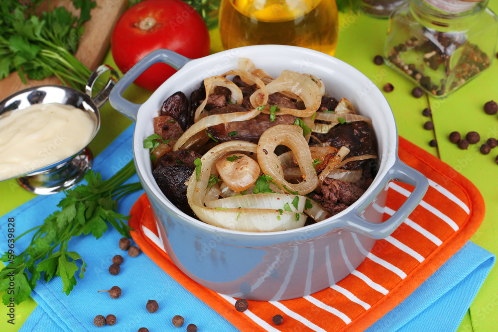 Fried chicken livers in pan on wooden table close-up