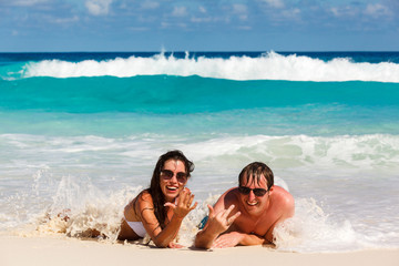 Young romantic couple laying on sandy beach